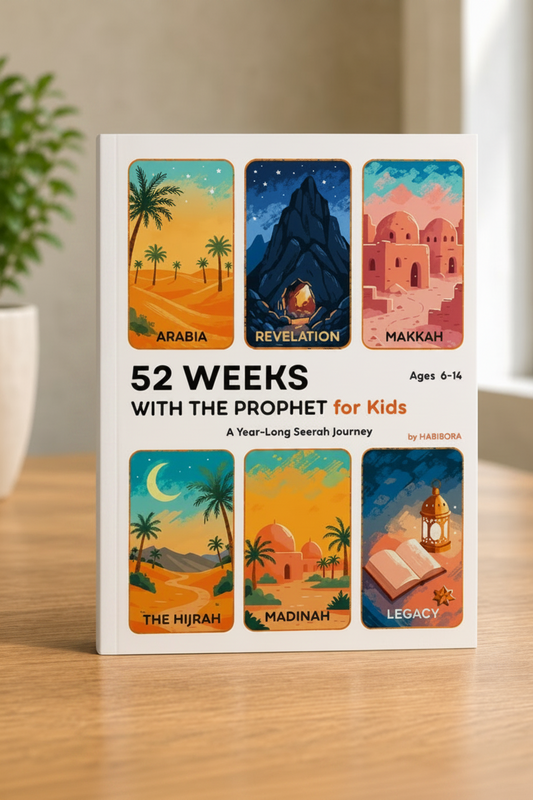 A children's book titled "52 Weeks with the Prophet for Kids" standing upright on a wooden surface. The cover shows six colorful illustrated panels with desert landscapes, mountains, domed buildings, a crescent moon, and an open book, plus a dark blue spine.